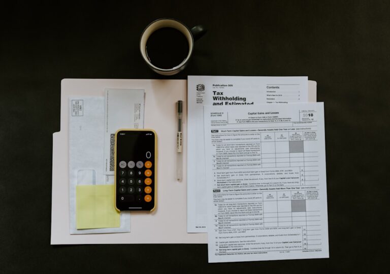 A person sorts through folders of financial paperwork on a home office desk.